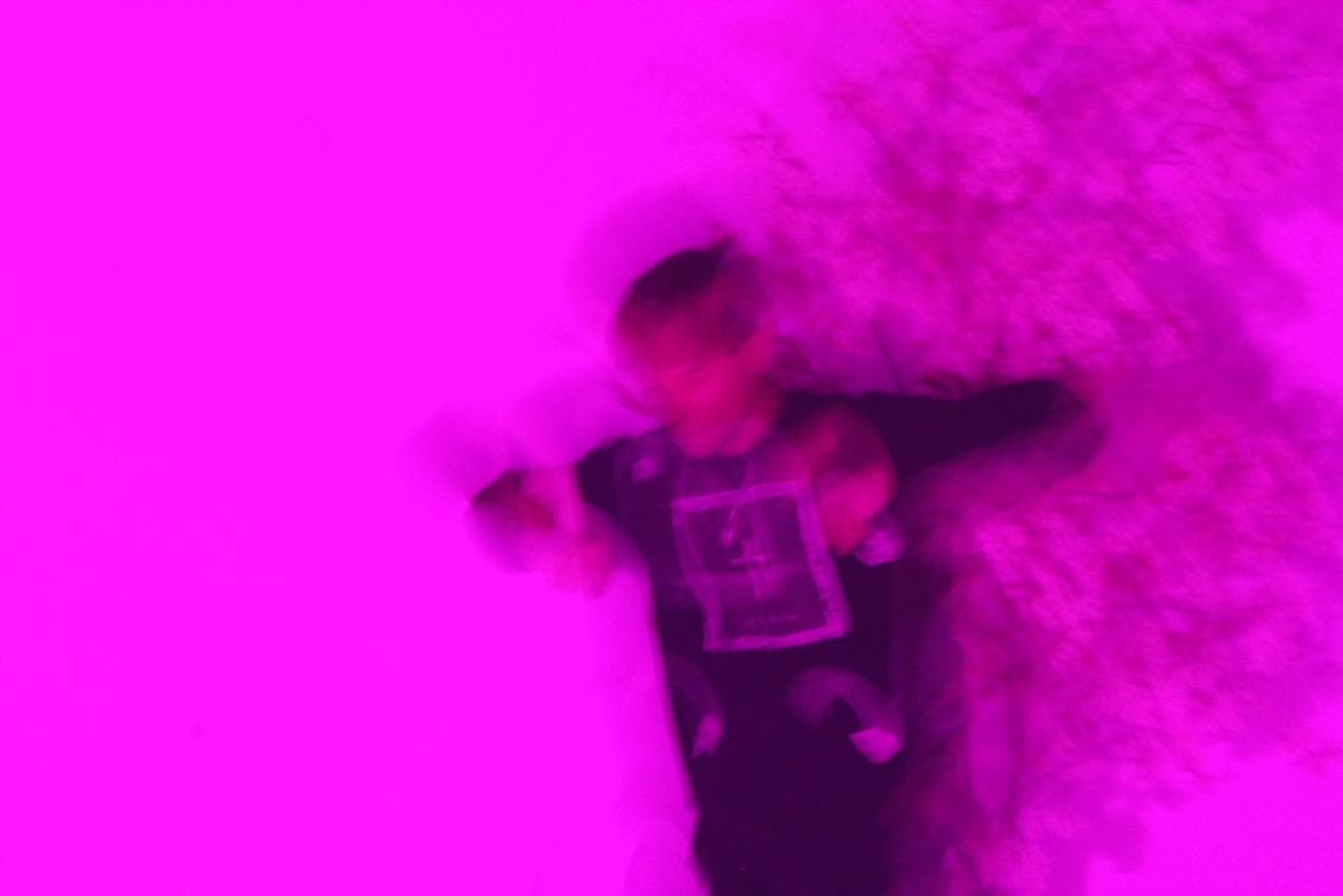 ADRO WHO? lying in the snow, blurred under magenta light